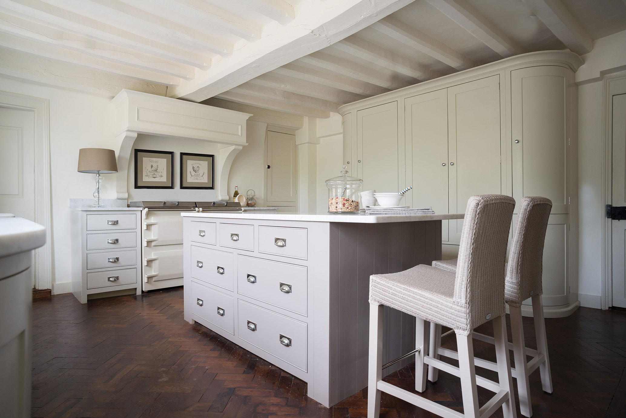 Helle, elegante Küche im Landhausstil mit großer Kücheninsel, Barhockern, Einbauschränken und Parkettboden