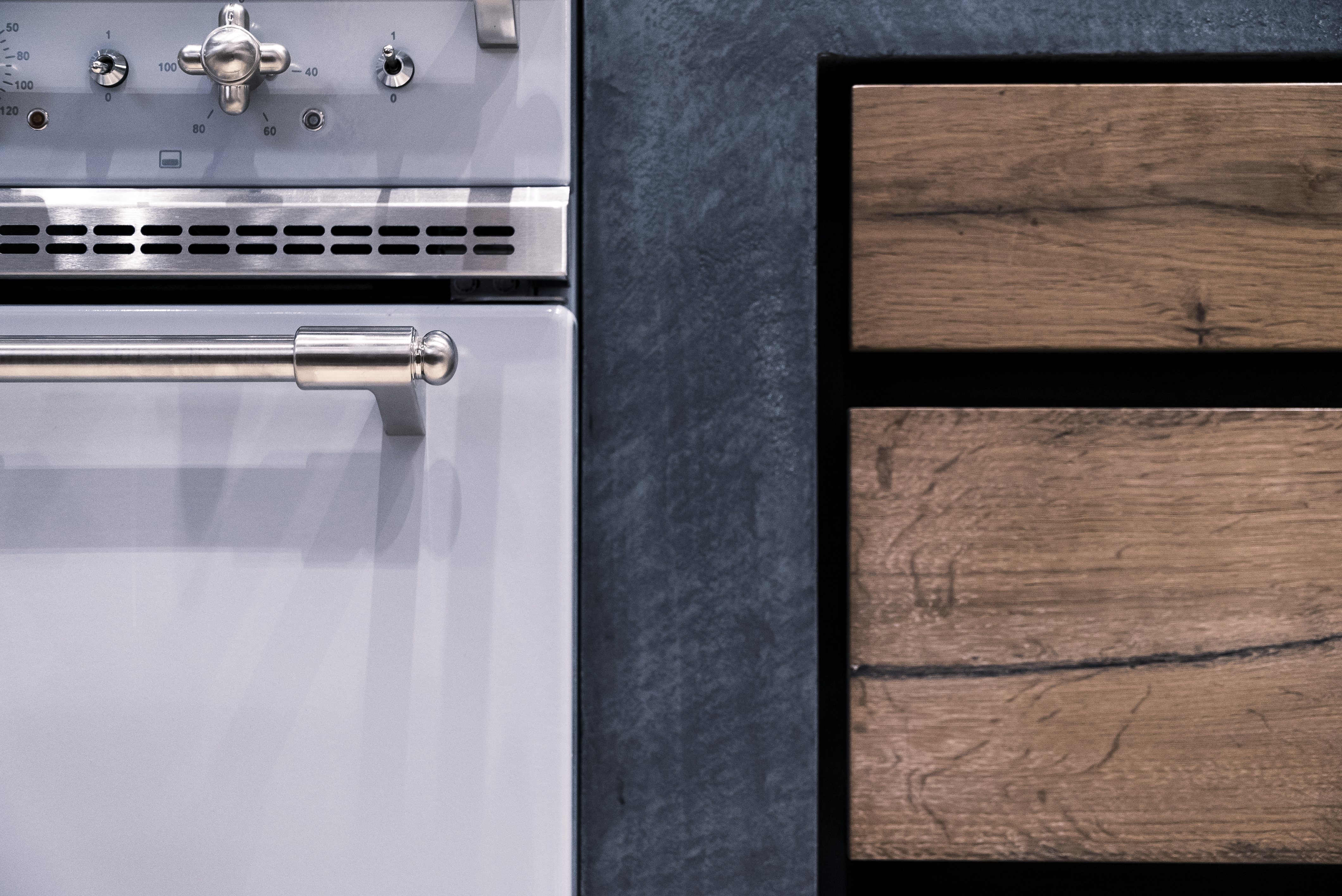 Detailansicht einer modernen Küchenzeile mit Edelstahlbackofen und Holzschubladen
