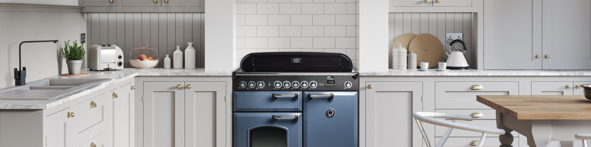 Helle, elegante Landhausküche mit blauem Herd, weißen Schränken, Marmorarbeitsplatte, Toaster, Wasserkocher und Dekoration