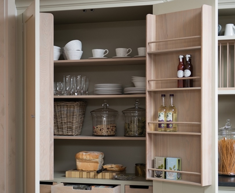 Holzschrank in einer Küche, gefüllt mit Tellern, Tassen, Gläsern, Vorratsgläsern, Flaschen und Brot