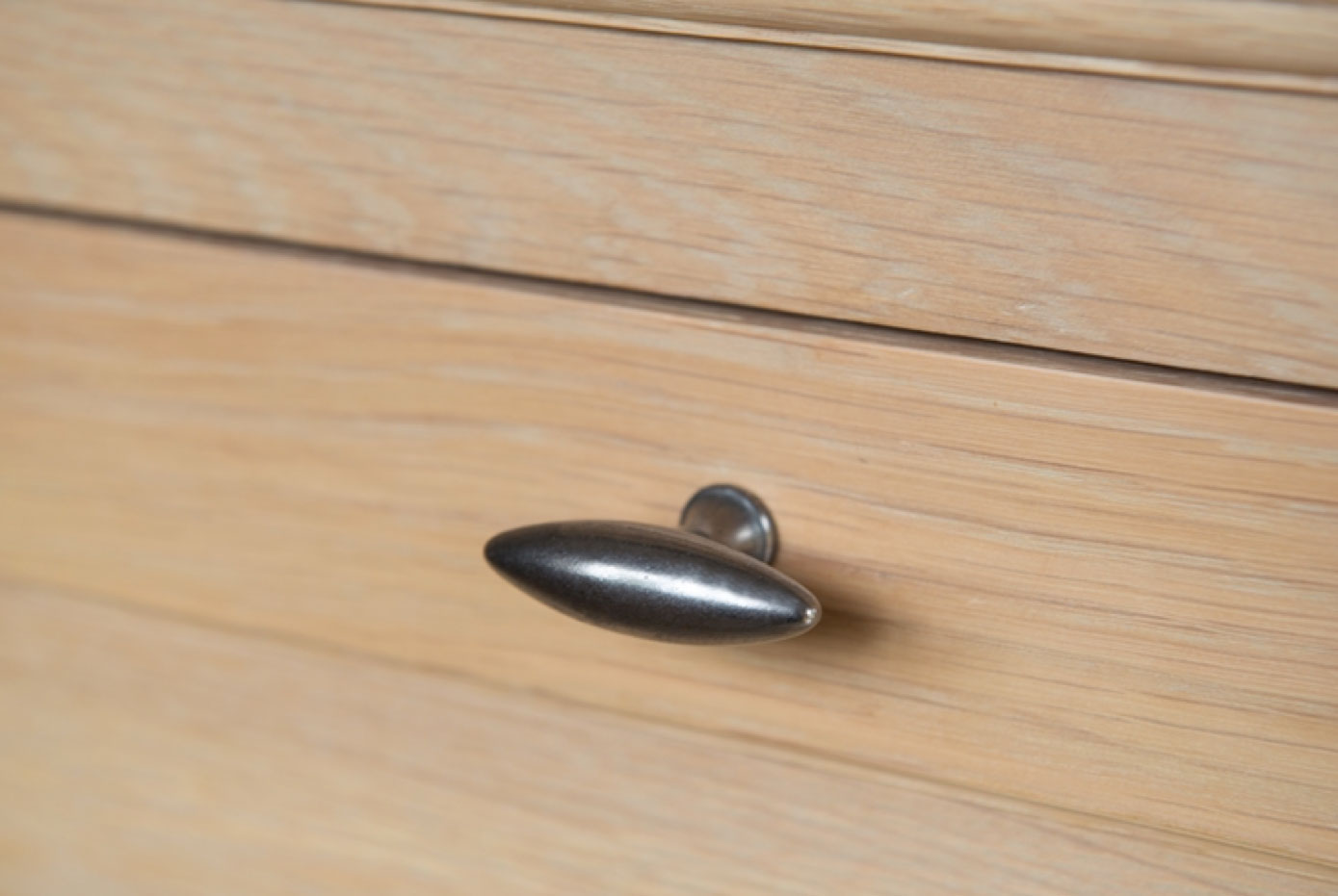 Detailaufnahme einer hellen Holzschublade mit modernem, silbernen Metallgriff