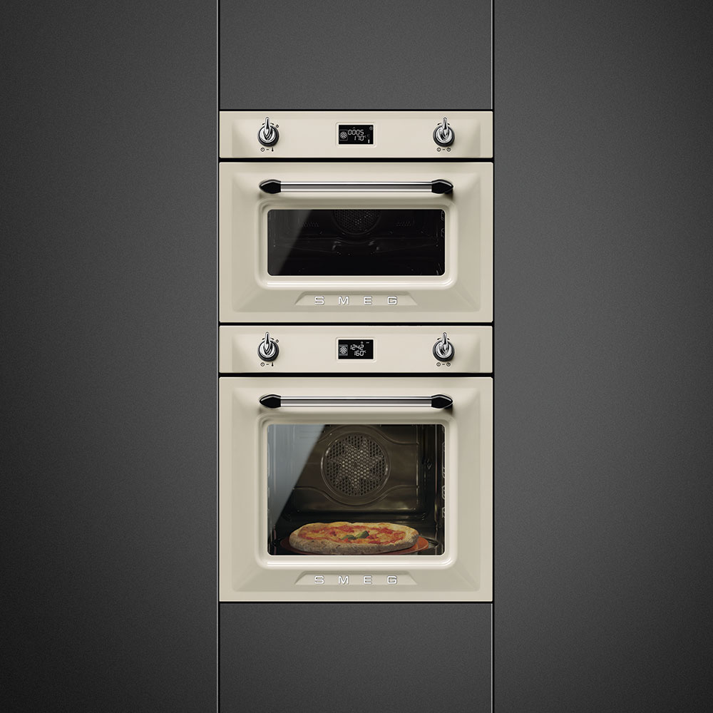 Zwei cremefarbene Smeg Backöfen im Retro-Design, im unteren Ofen wird eine Pizza gebacken
