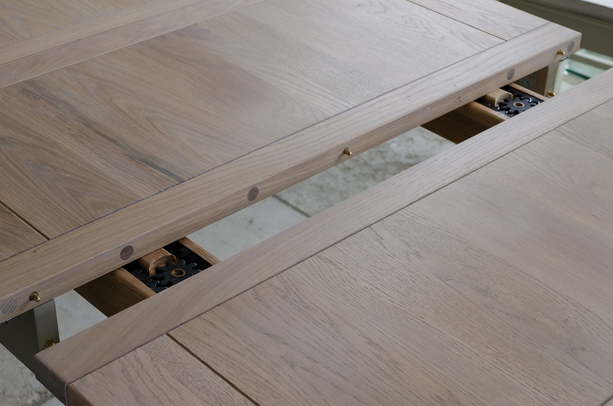 Detailaufnahme eines ausziehbaren Holztisches mit offenem Mechanismus zur Verlängerung der Tischplatte