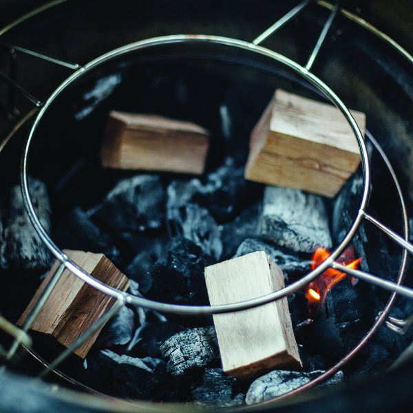 Nahaufnahme von Holzstücken und glühender Holzkohle auf einem Grillrost, bereit zum Grillen oder Räuchern
