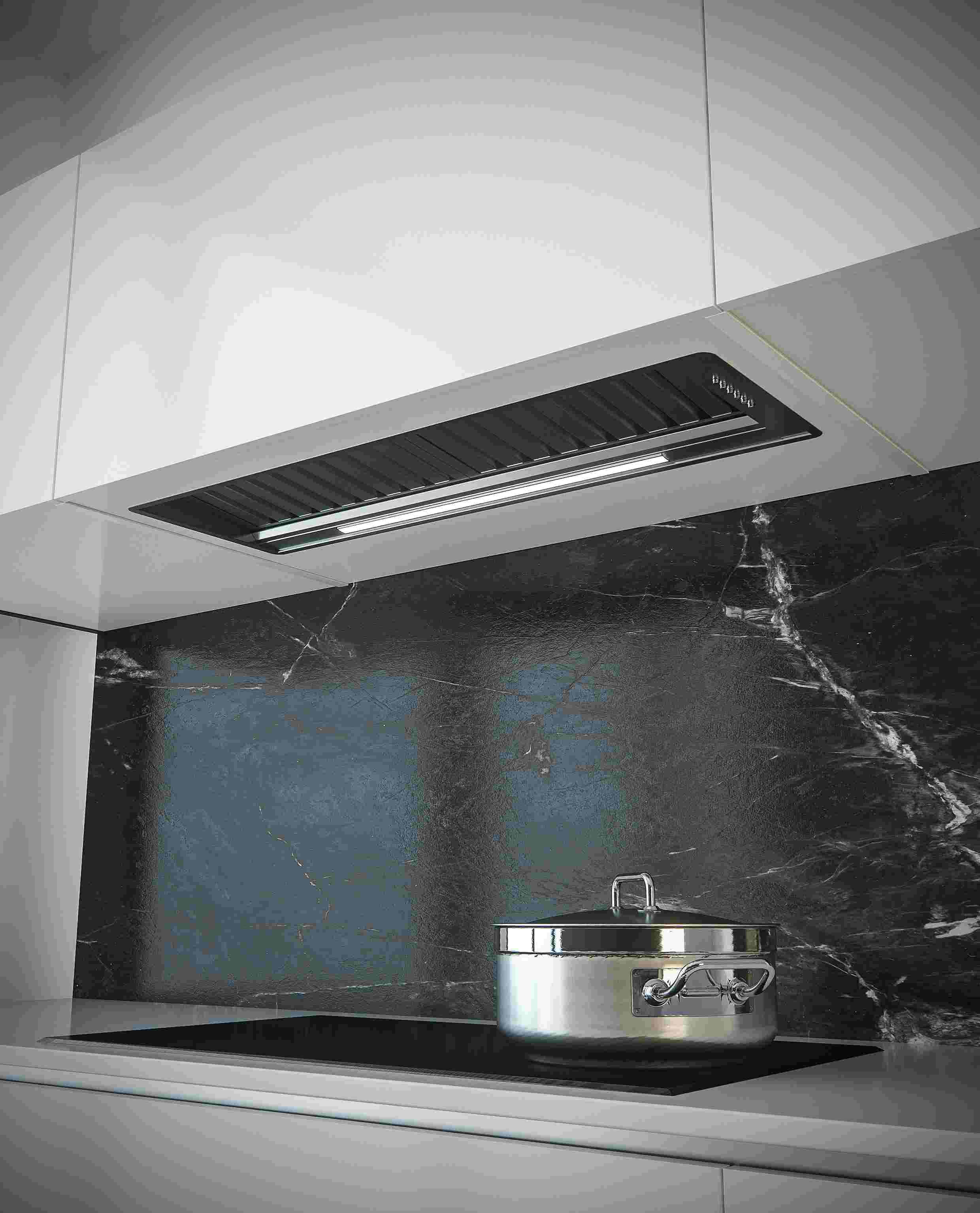 Elegante Einbau-Dunstabzugshaube über einem Induktionskochfeld mit Edelstahl-Topf in moderner Küche