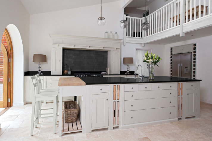 Helle, moderne Wohnküche mit großer Kochinsel, Barhockern, Edelstahlgeräten, schwarzen Arbeitsplatten und stilvollen Accessoires