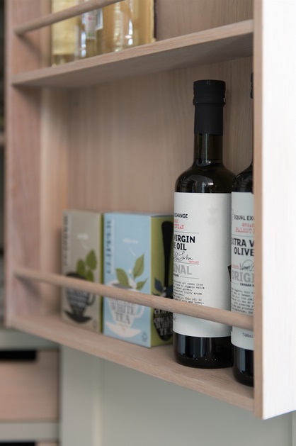 Eine Flasche Bio-Olivenöl Extra Vergine neben Teeboxen in einem hellen Küchenschrank. Ideal zur Aufbewahrung von hochwertigen Lebensmitteln.