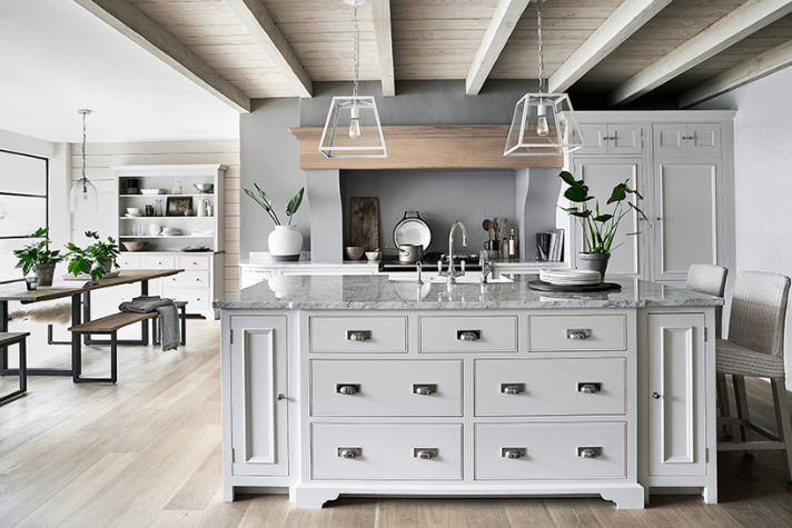 Helle, moderne Landhausküche mit zentraler Kücheninsel, Holzbalken-Decke, Esstischbereich und stilvoller Dekoration