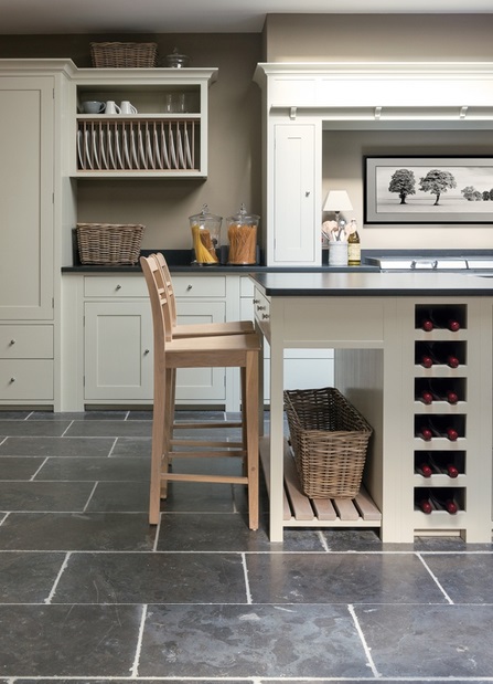 Helle Landhausküche mit zentraler Kücheninsel, Holzbarhocker, Weinregal, offenen Regalen und stilvoller Dekoration