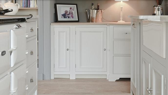 Helle, moderne Küche mit weißen Schränken, Arbeitsplatte, Tischlampe, Dekoration und Einbauherd im Landhausstil
