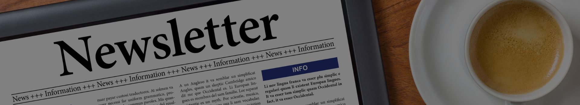 Ansicht eines Tablets mit dem Titel Newsletter auf dem Bildschirm, daneben steht eine Tasse Kaffee auf einem weißen Unterteller auf einem Holztisch.
