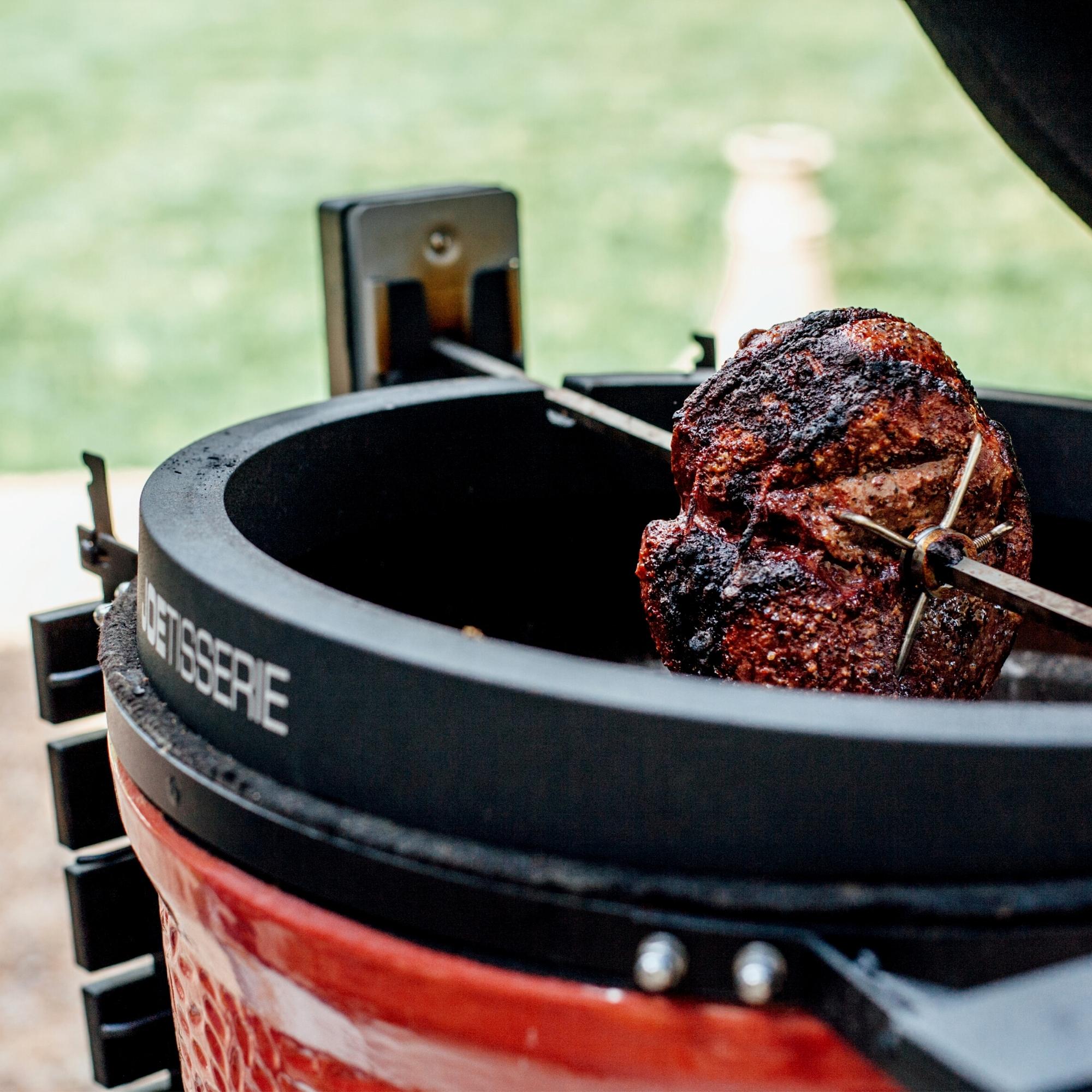 Fleischstück wird auf einem Drehspieß in einem Keramikgrill mit Rotisserie-Funktion knusprig gegrillt
