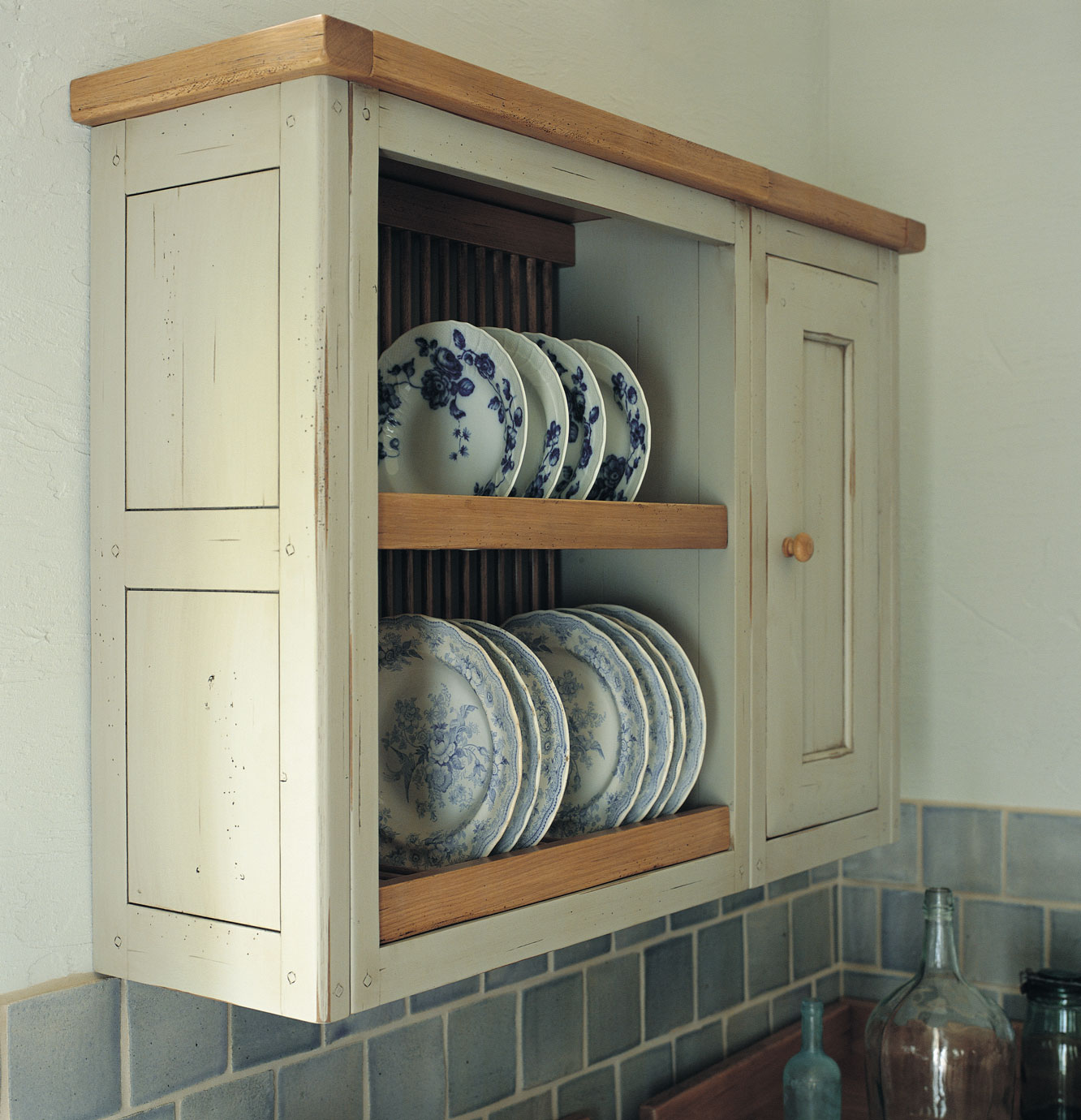 Hängeschrank aus hellem Holz im Landhausstil mit offenem Regal, in dem dekorative Porzellanteller mit blauem Blumendekor stehen