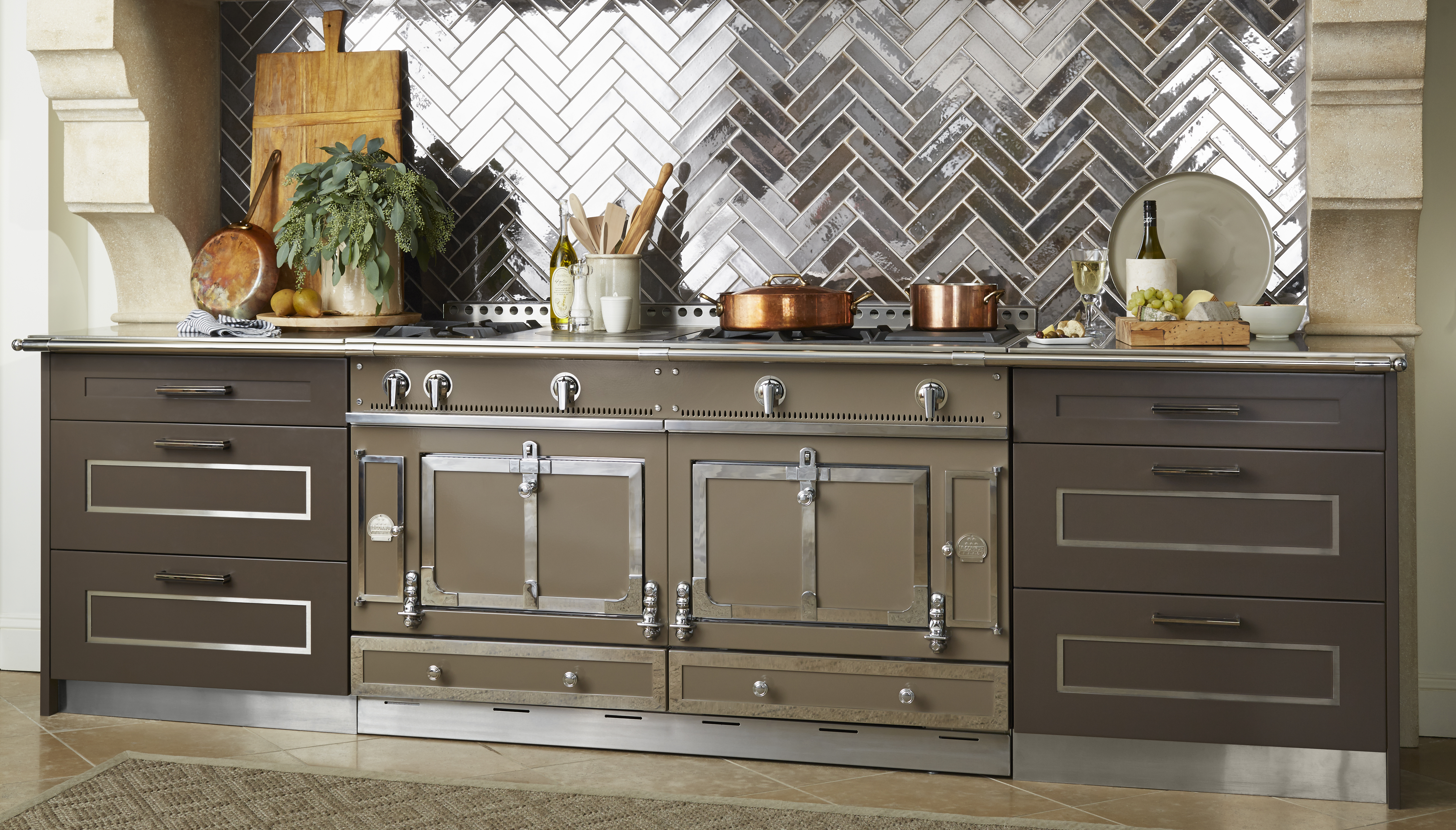 Großer Premium-Küchenherd mit Kupfertöpfen, Küchenutensilien, Schneidebrett, und Fliesenrückwand in einer eleganten Einbauküche