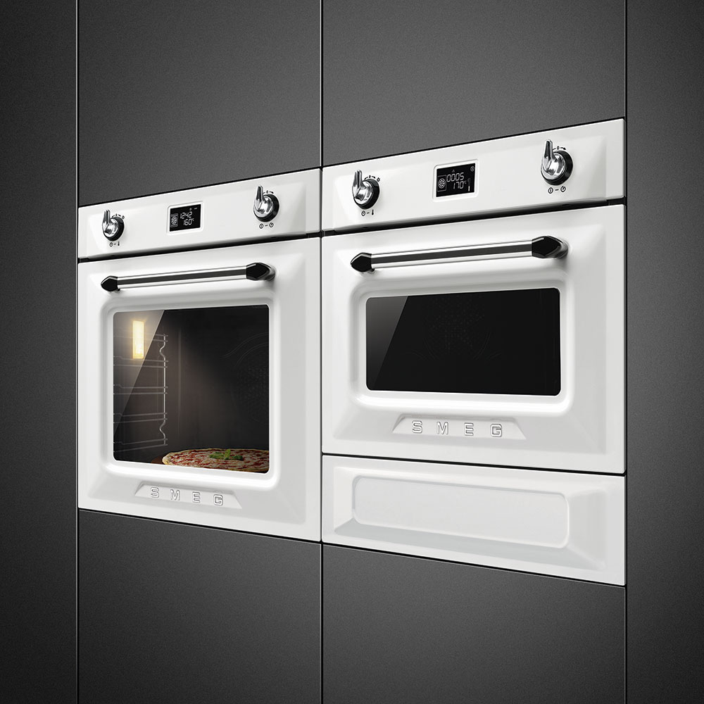 Zwei SMEG Einbau-Backöfen in Weiß, in eine schwarze Küchenfront integriert. Im unteren linken Ofen ist eine Pizza sichtbar gebacken.