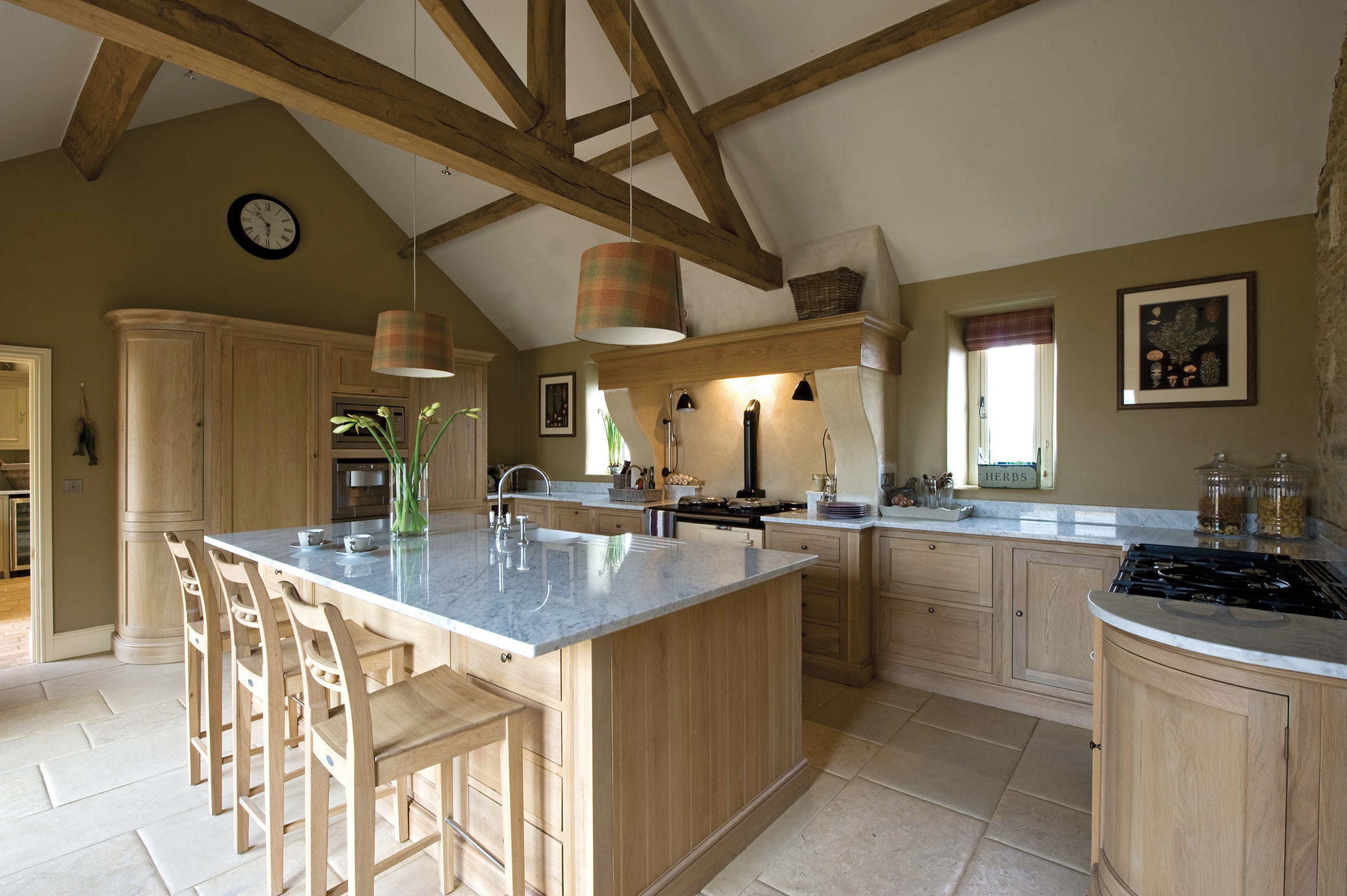 Große Landhausküche mit Holzmöbeln, Kücheninsel mit Marmorarbeitsplatte, Holzbalken-Decke und stilvollen Hängelampen