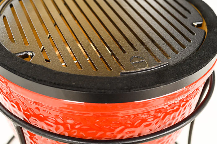 Nahaufnahme eines roten Keramikgrills mit schwarzem Grillrost aus Gusseisen