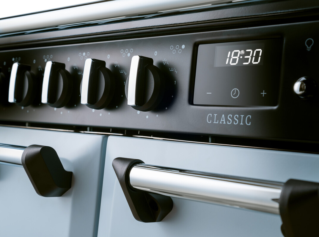 Detailansicht: Classic Standherd/Range Cooker in Hellblau mit Chromgriffen, mehreren Drehknöpfen und digitaler Uhr 18:30 – robuste Bedienblende für Kochfelder und Backofen