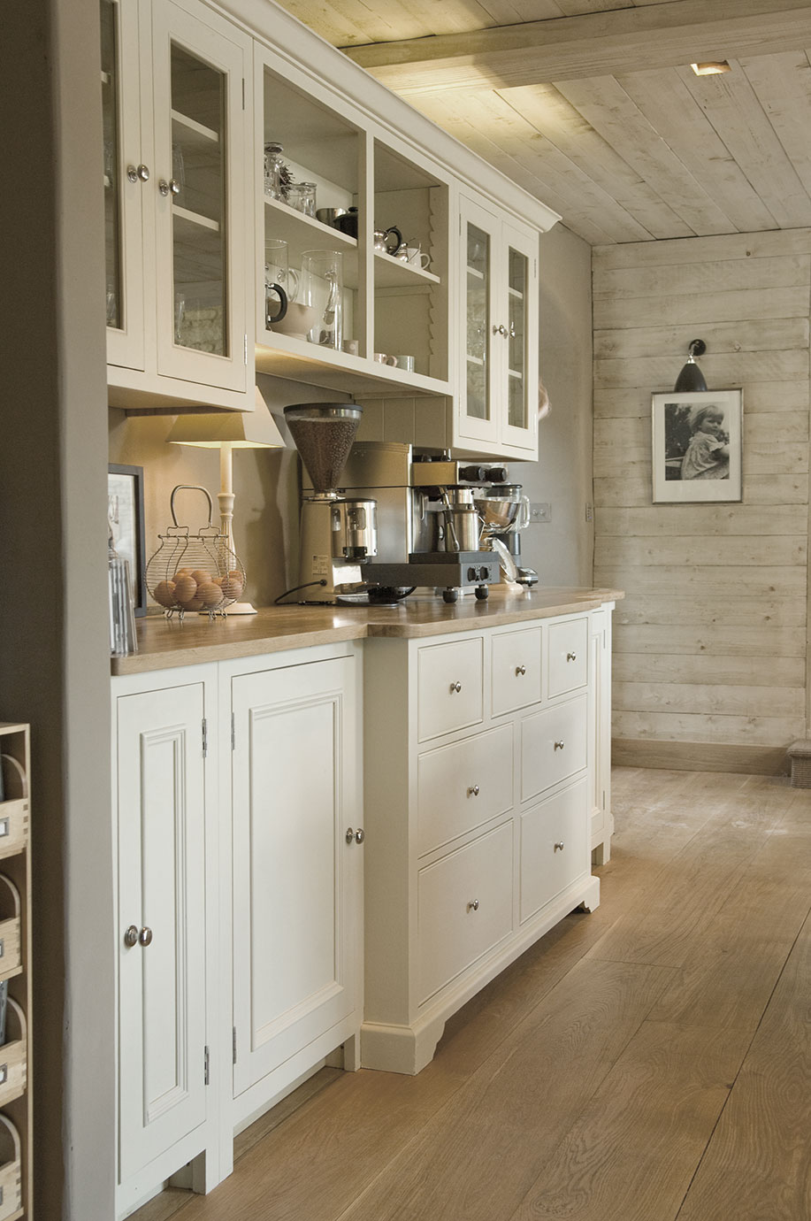 Moderne Landhausküche mit weißen Schränken, Holzarbeitsplatte, Kaffeemaschine und stilvoller Dekoration