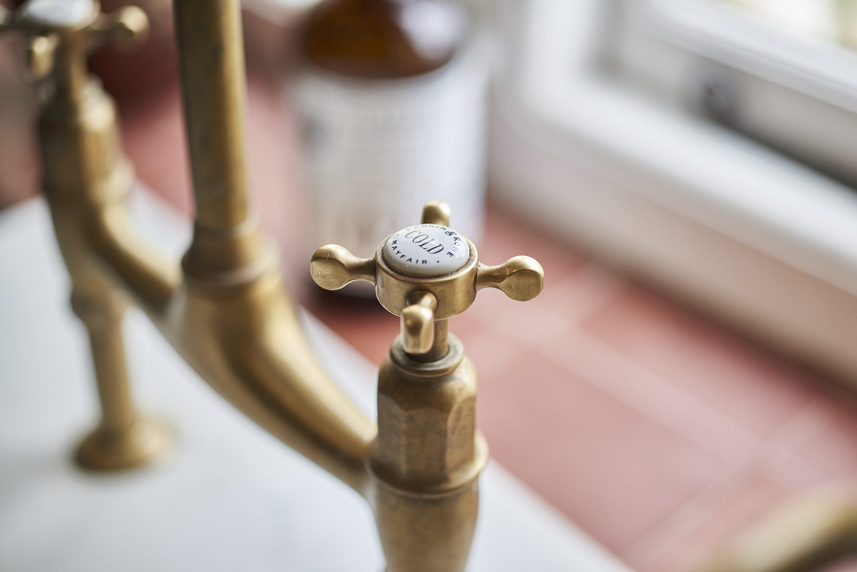 Detailaufnahme eines klassischen Messing-Wasserhahns mit Kreuzgriff und der Aufschrift 'Cold', geeignet für Küche oder Bad