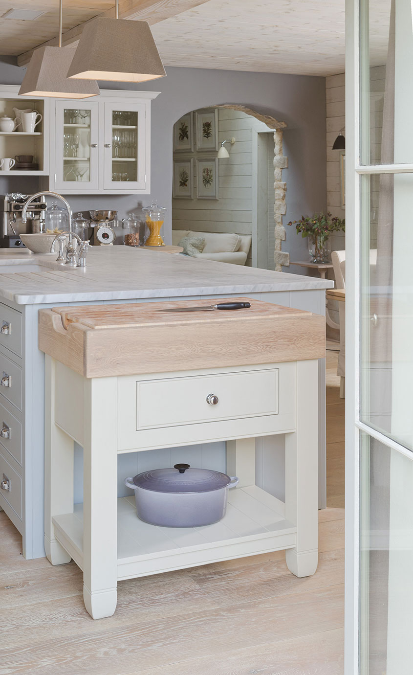 Küchenblock aus Holz mit großer Schneidefläche, Schublade und einem lila Bräter im Regal, in moderner Landhausküche