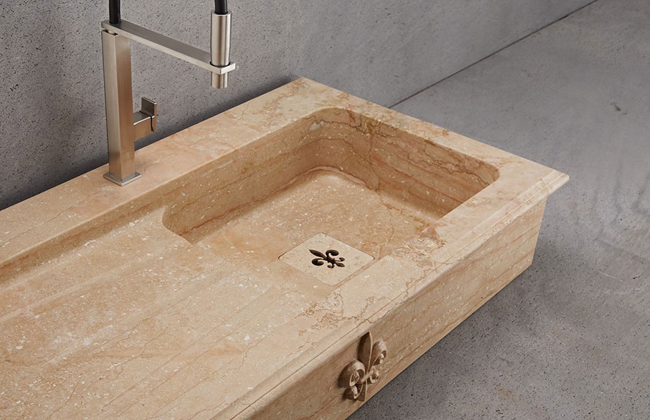 Waschbecken aus beige-gelbem Naturstein mit rechteckiger Form, eingelassener moderner Armatur und dekorativem Fleur-de-Lis-Motiv